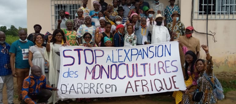 A group of people holding a banner opposing tree plantations