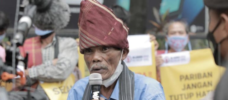 A Batak man with typical headgear and a microphone