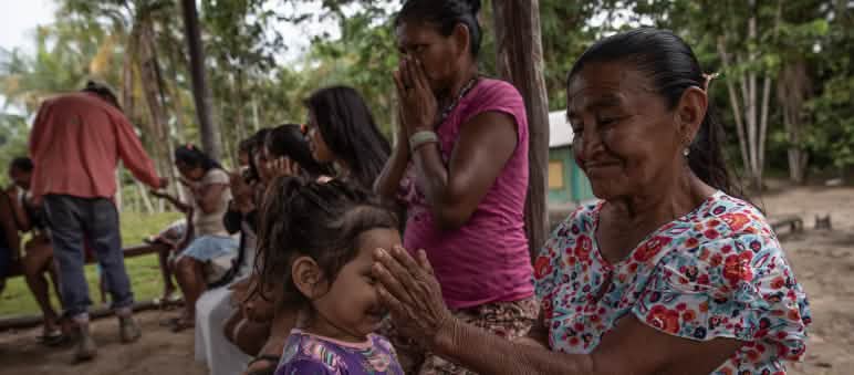 A young girl smells the essential oils in an Indigenous woman’s hand