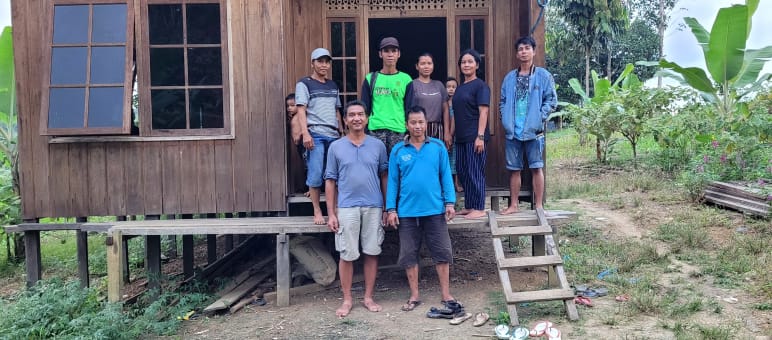 Seven people in front of a wooden house
