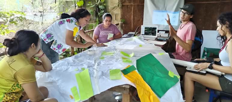 Five women around a table working on materials