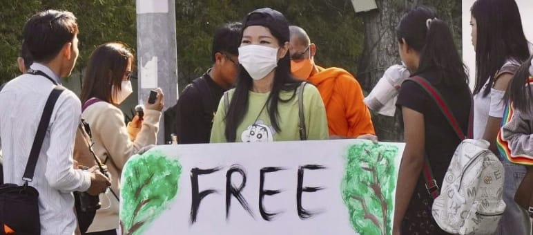 Young woman holding a large placard with the text “Free Mother Nature Activist!”