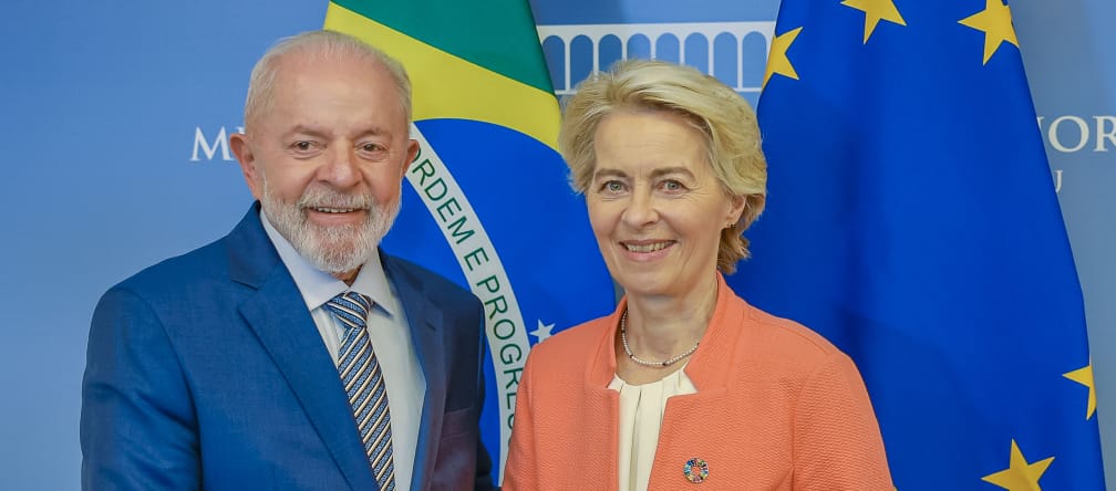 The President of the European Commission, Ursula von der Leyen, and Brazil’s President Lula da Silva shake hands in front of national flags