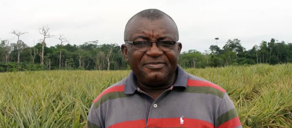 Odey Oyama in front of a pineapple plantation