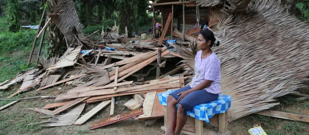 A villager sitting in front of the ruins of her house