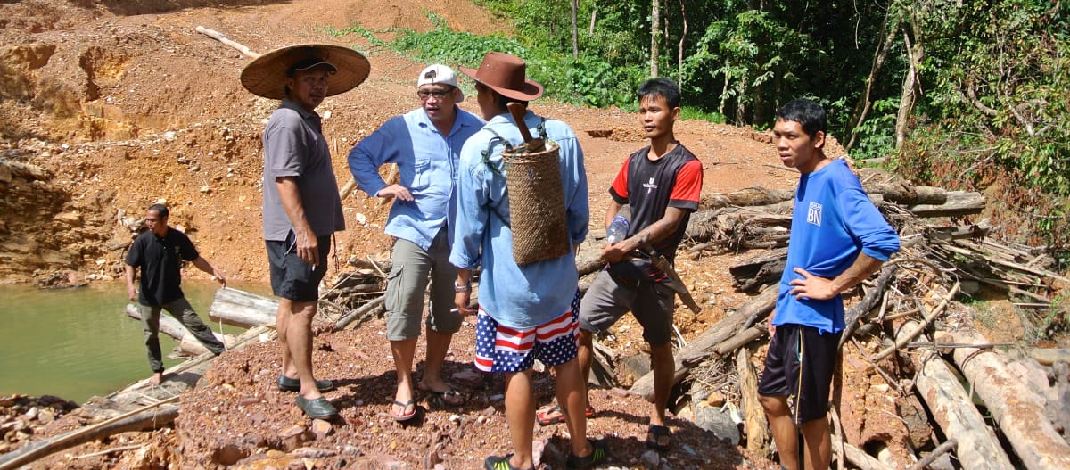 Indigenous people stand on a dirt road illegally built by loggers in Sarawak