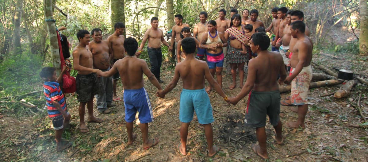 Indigenous Ka'apor people – children, women and men – join hands and form a circle in the rainforest