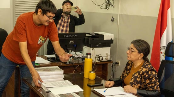 A human rights activist hands the petition to the President of the Indigenous Institute, who is sitting at her desk