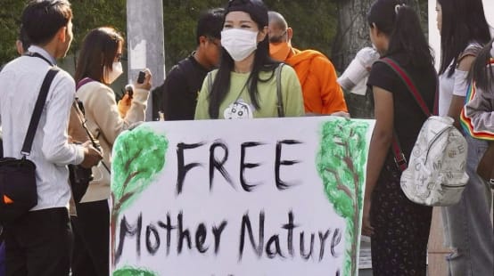 Young woman holding a large placard with the text “Free Mother Nature Activist!”