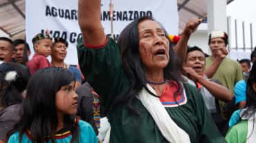 Indigenous people protesting, a banner in the background