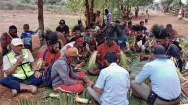 A group of Papuans sitting on palm leaves