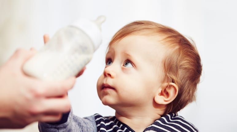 A worried-looking baby pushing its bottle away