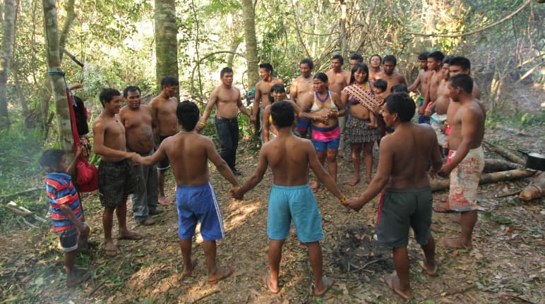 Indigenous Ka'apor people – children, women and men – join hands and form a circle in the rainforest