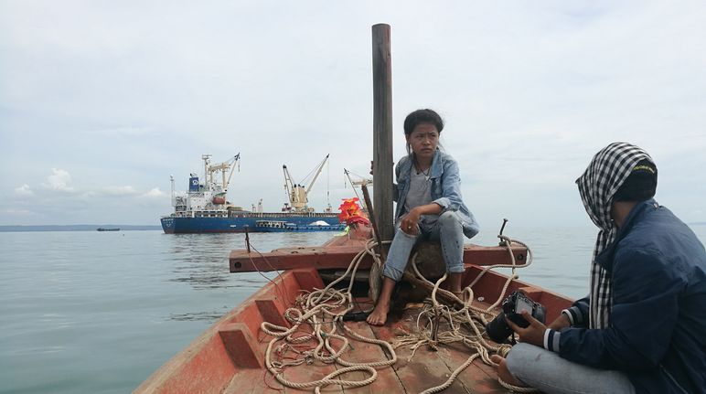 Two activists in a boat observing a dredger