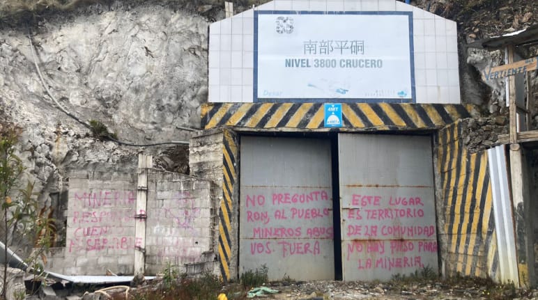 Closed entrance gate to a mine tunnel with protest graffiti