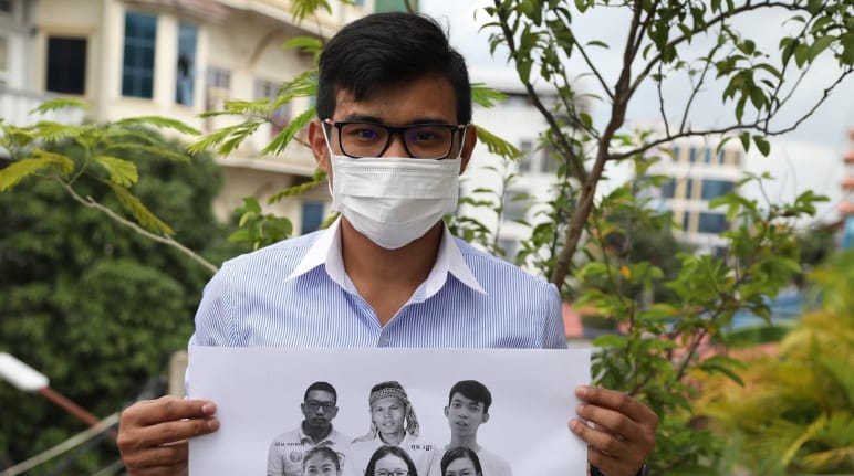 A young man holds up a poster with the six jailed activists