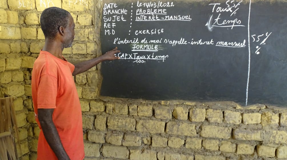 Lessons in the village of Bekombo – the teacher explains monthly interest Teacher in a village school in the Democratic Republic of the Congo