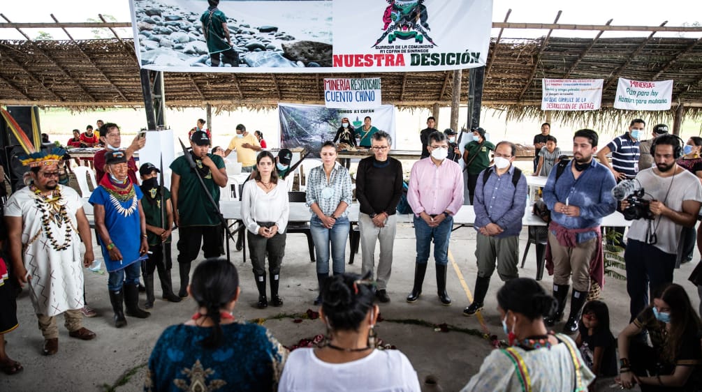 Gathering in a rainforest village: a group of people form a circle under a banner