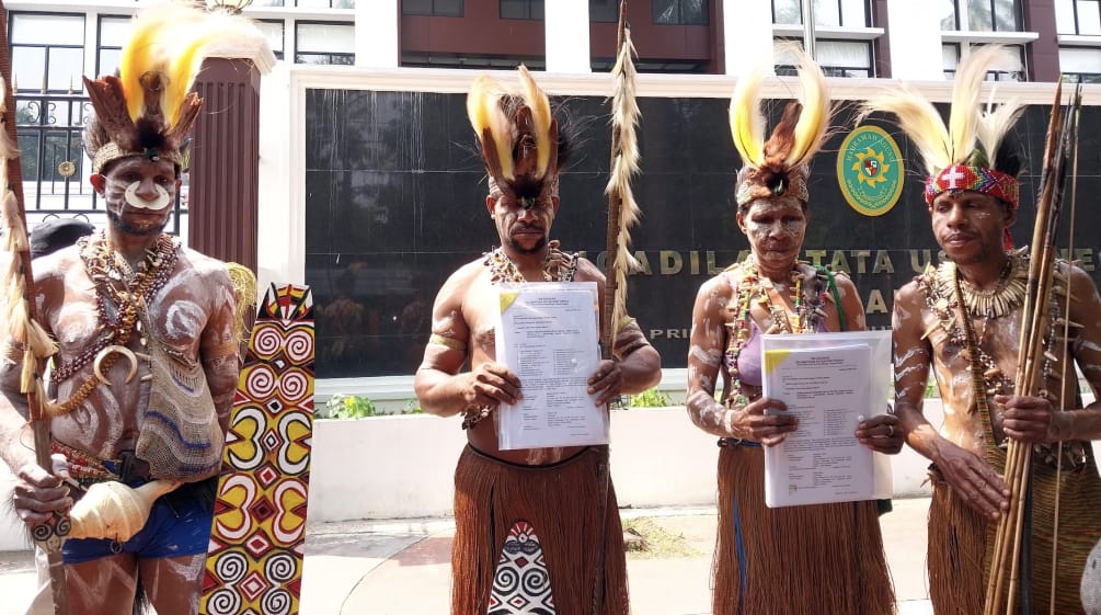 four Papuans in traditional dress in front of the courthouse