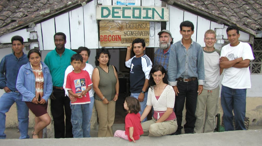 Group of people from DECOIN and Rainforest Rescue in front of a wooden hut with the inscription DECOIN