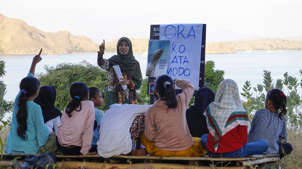 Girls with their backs to the camera learning about the Komodo dragon