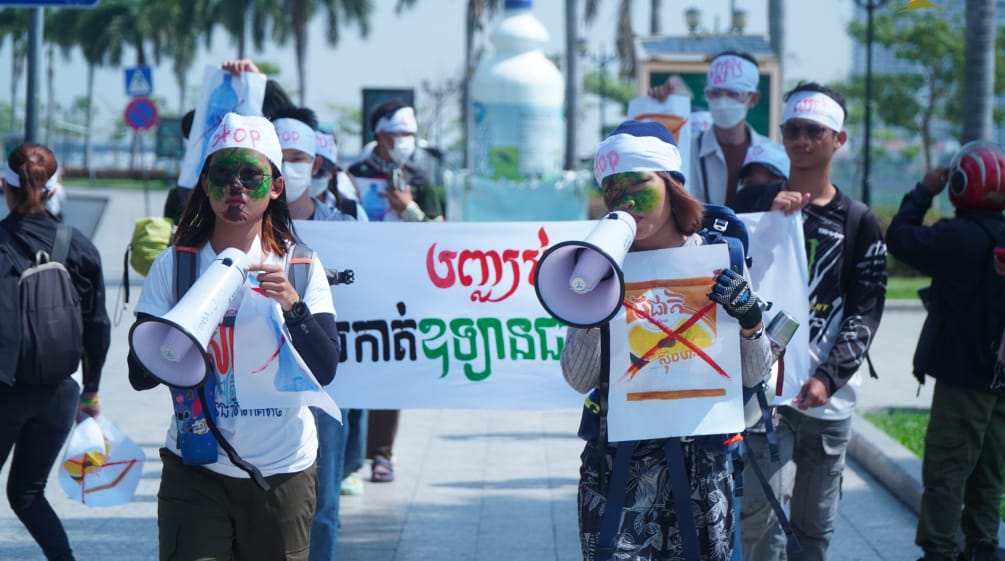 A group of young students walks through a street with megaphones and banners