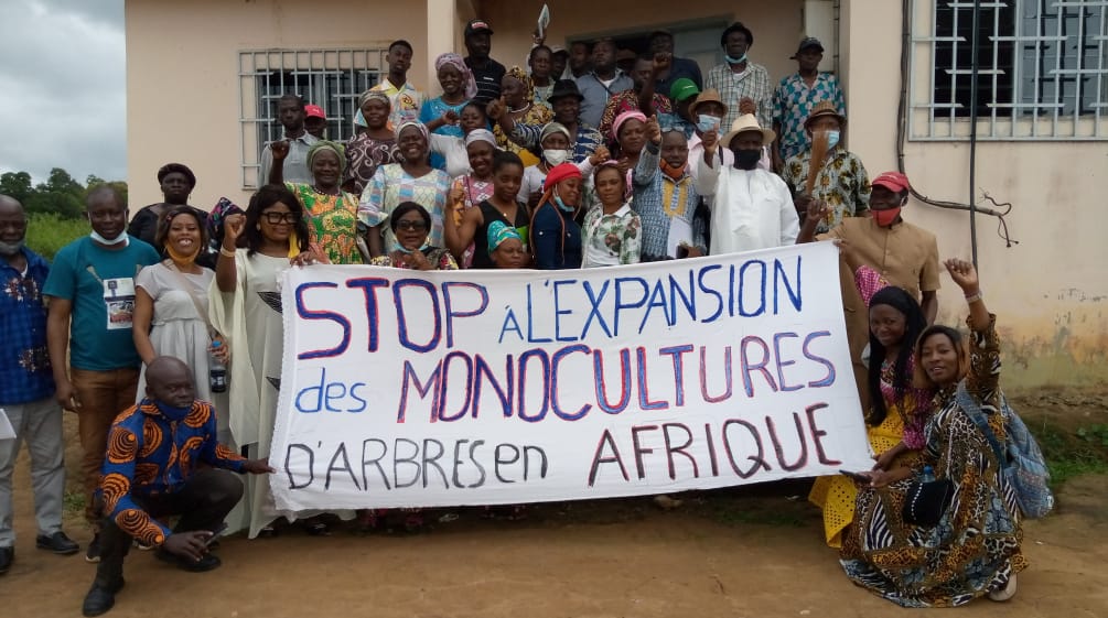 A group of people holding a banner opposing tree plantations