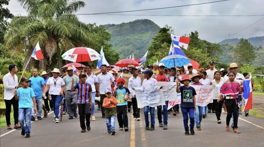 Protesters march with banners, national flags and umbrellas on a country road in Panama