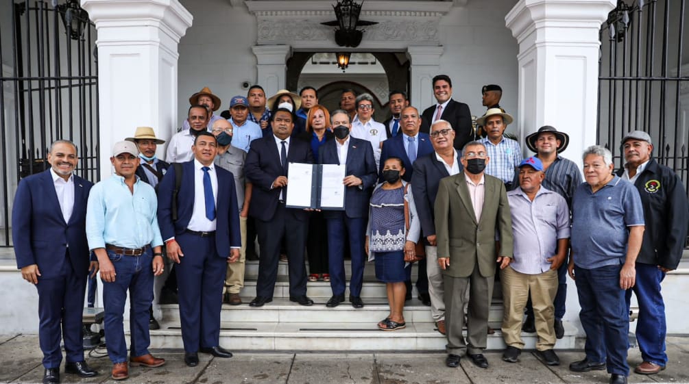 A group of around 20 people, with the President of Panama in the center of the picture, present the signed law at the entrance to the presidential palace