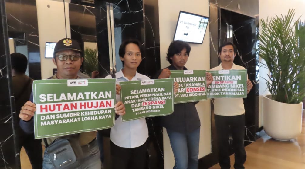 Four men hold placards reading “Save the forest and livelihoods of the people of Loeha Raya”