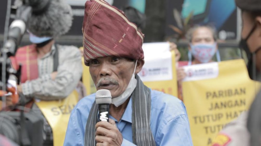 A Batak man with typical headgear and a microphone