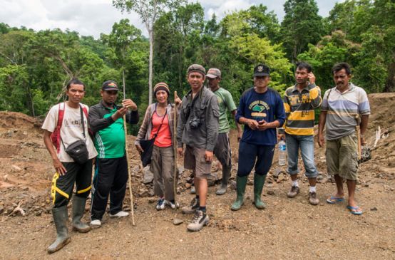 A group of activists and villagers standing together on a clearing