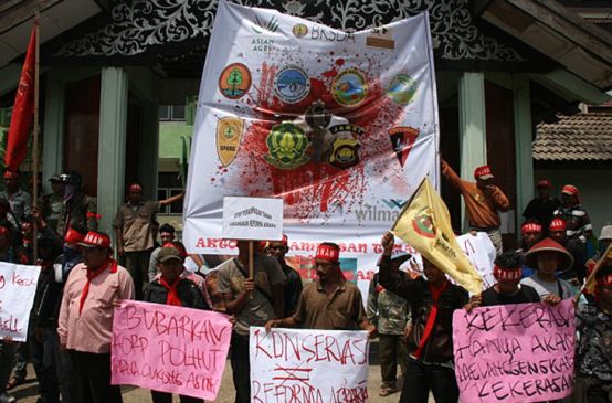Protesters walk with banners against oil companies