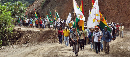 Indians on a protest march with flags in their hands walking up a gravel road