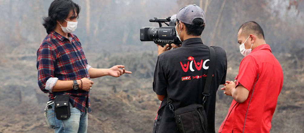 “1,000 hectares of peat forest were burned here,” explains environmental activist Feri Irawan. “But we were still able to save most of the forest.” A man being interviewed with a burning rainforest in the background
