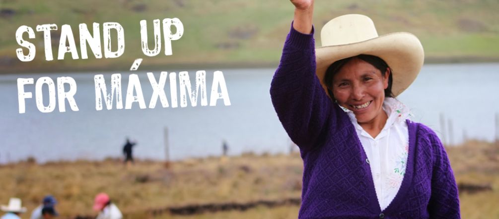 Maxima Acuña smiles and raises her right fist. Other farmers and the Blue Lagoon can be seen in the background.