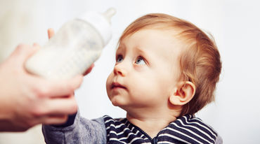 A worried-looking baby pushing its bottle away