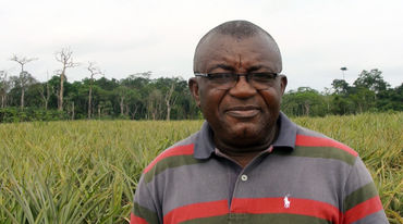 Odey Oyama in front of a pineapple plantation