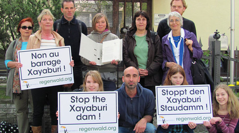 People infront of the embassy in Berlin holding protest signs against the dam