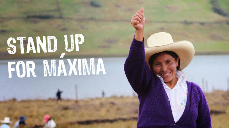 Maxima Acuña smiles and raises her right fist. Other farmers and the Blue Lagoon can be seen in the background.