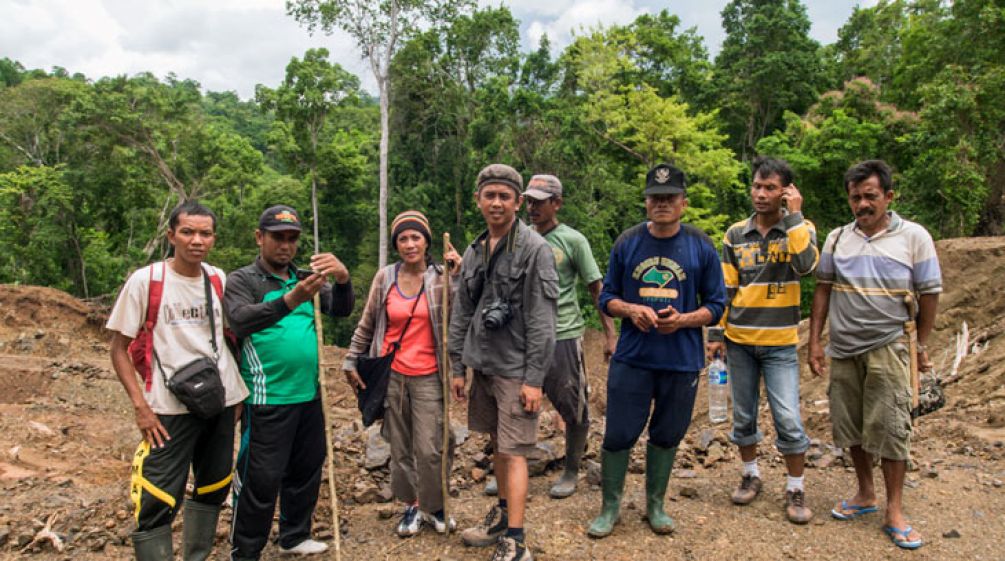 A group of activists and villagers standing together on a clearing