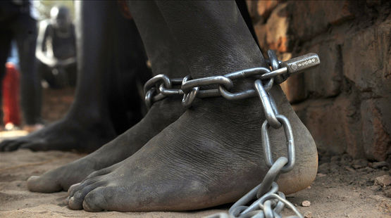 A pair of bare feet bound with chains and a padlock